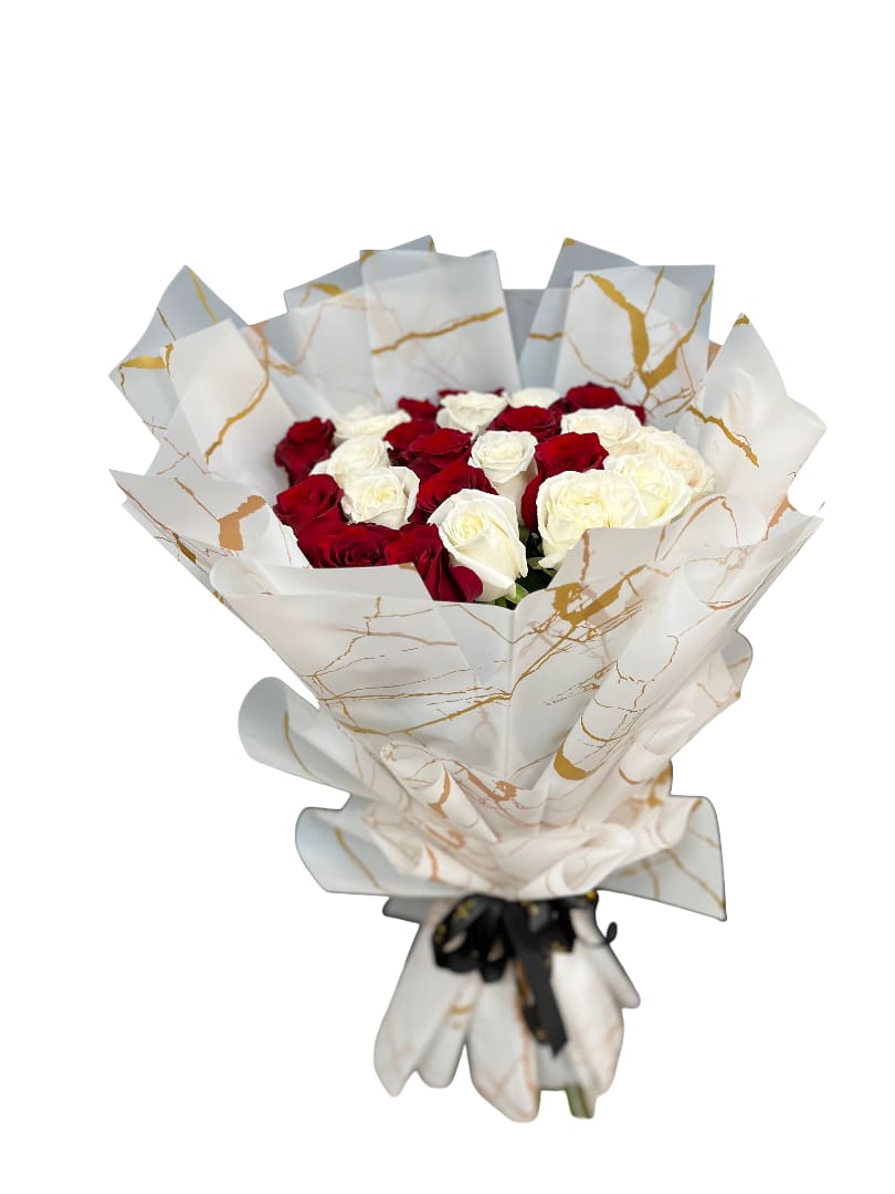 Bouquet of red and white roses wrapped in white paper with gold accents