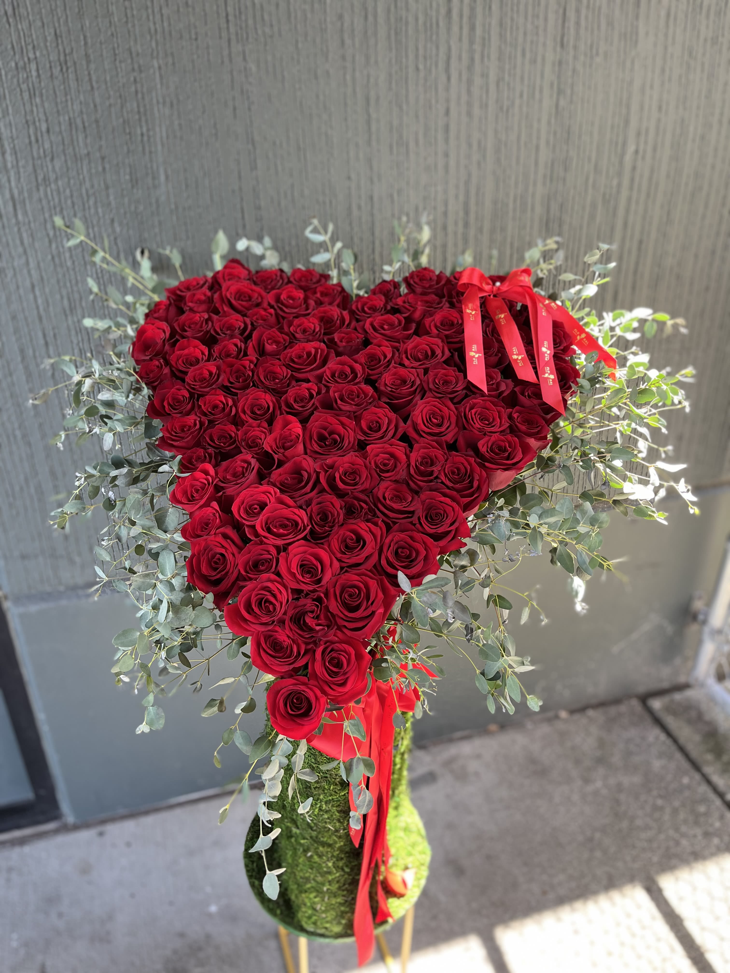 Elegant Floral Stand - A tall floral stand beautifully arranged with lush greenery and vibrant seasonal blooms. Perfect for weddings, ceremonies, and formal events