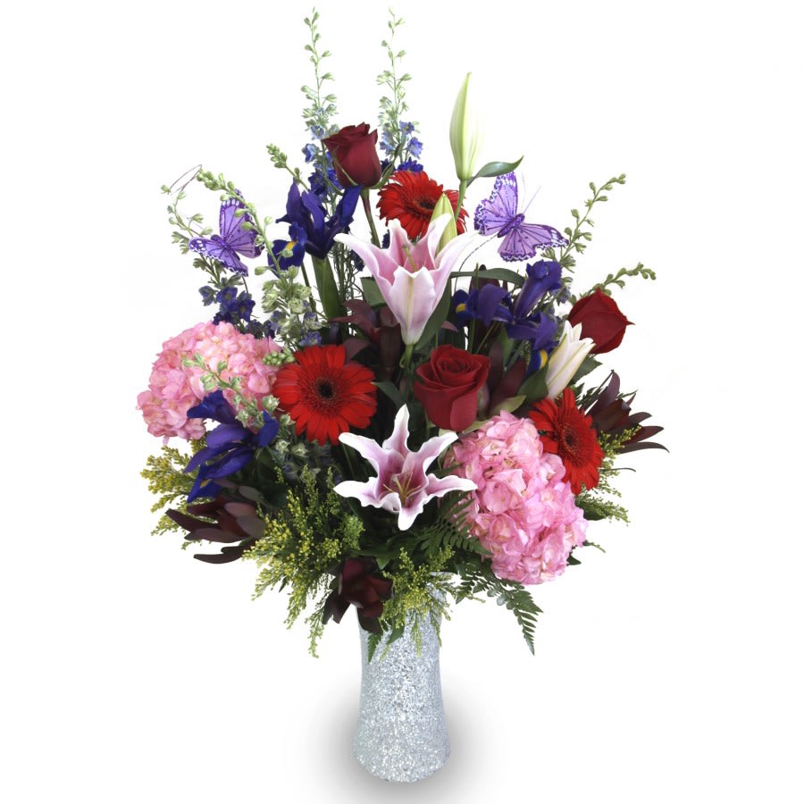 Mixed bouquet of lilies, roses, gerbera daisies, and hydrangeas in a glittery vase