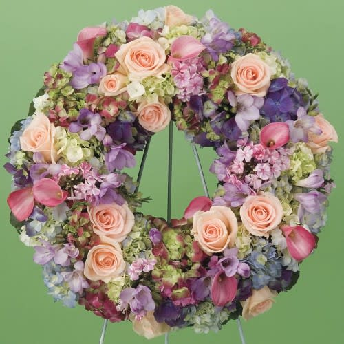 Circular floral wreath with pink roses and purple blooms on a stand