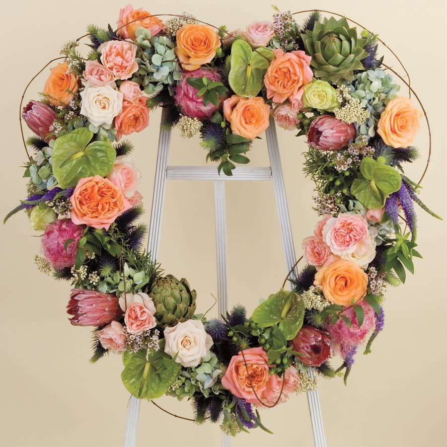 Heart-shaped floral wreath with roses and succulents on a stand