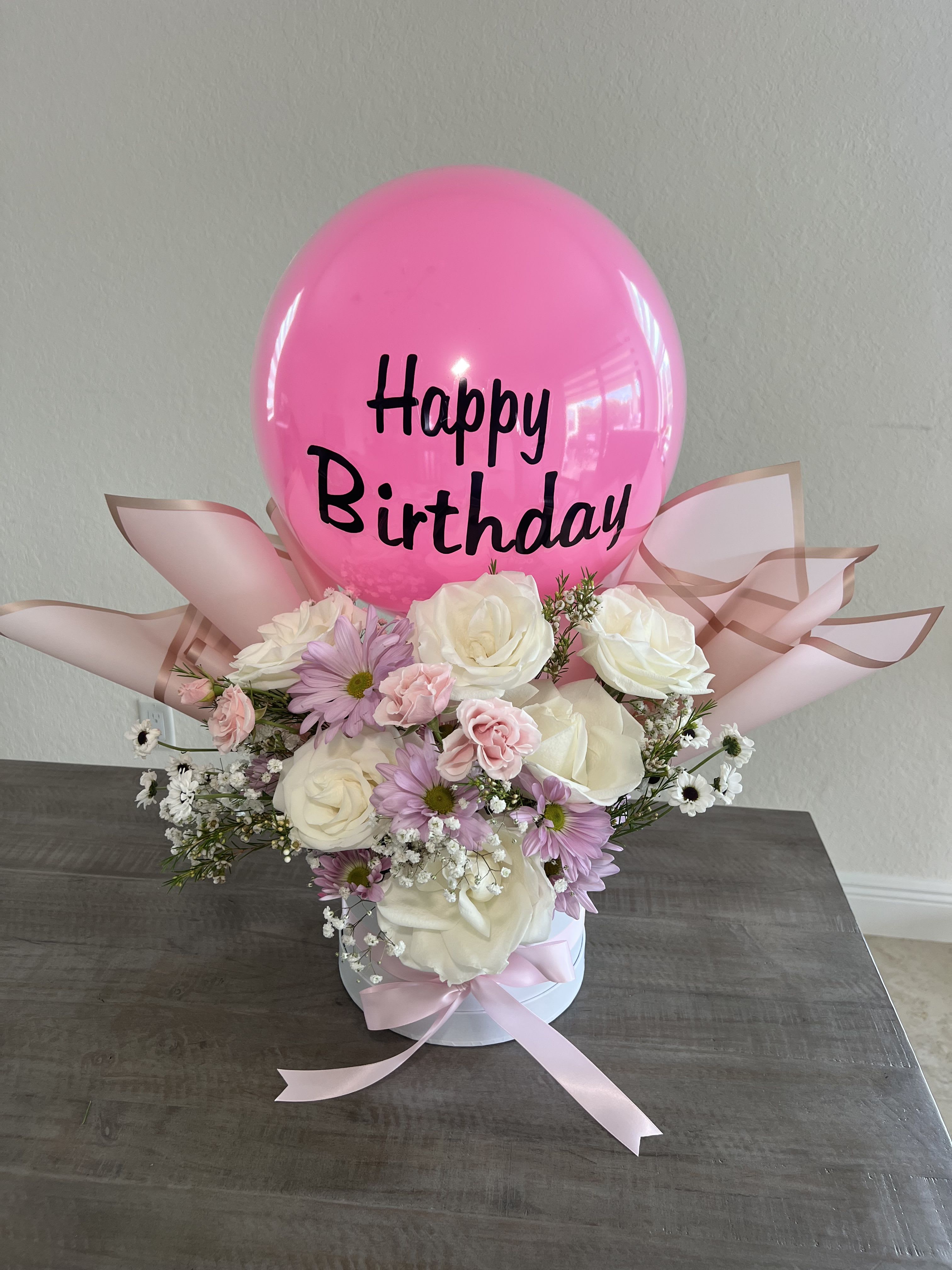 Pink birthday balloon above a pastel flower arrangement in a white box