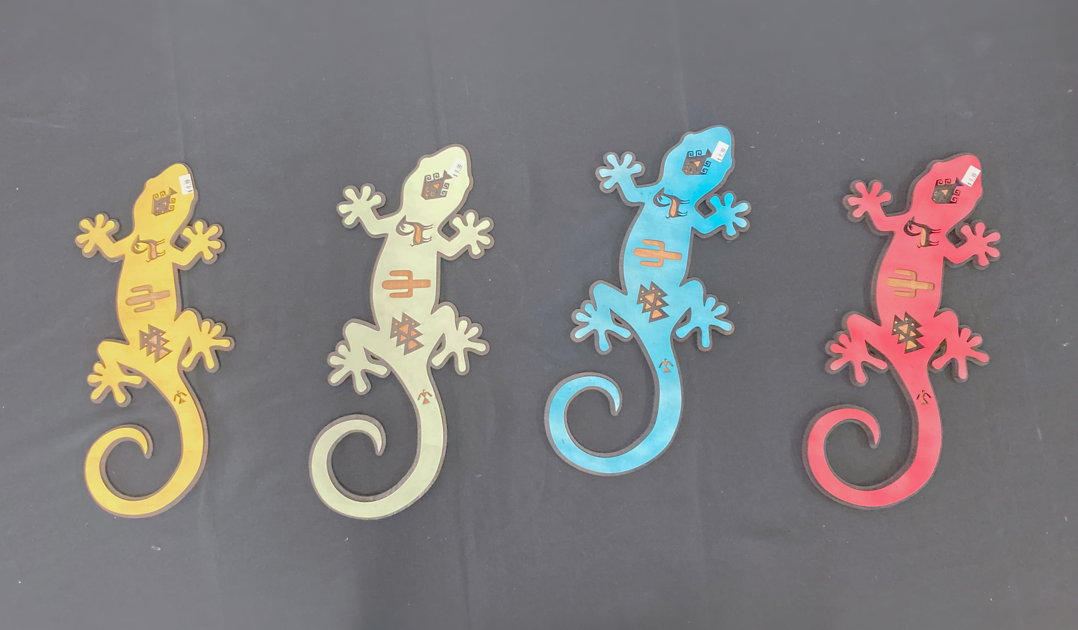 Four colorful gecko-shaped cutouts on a dark background