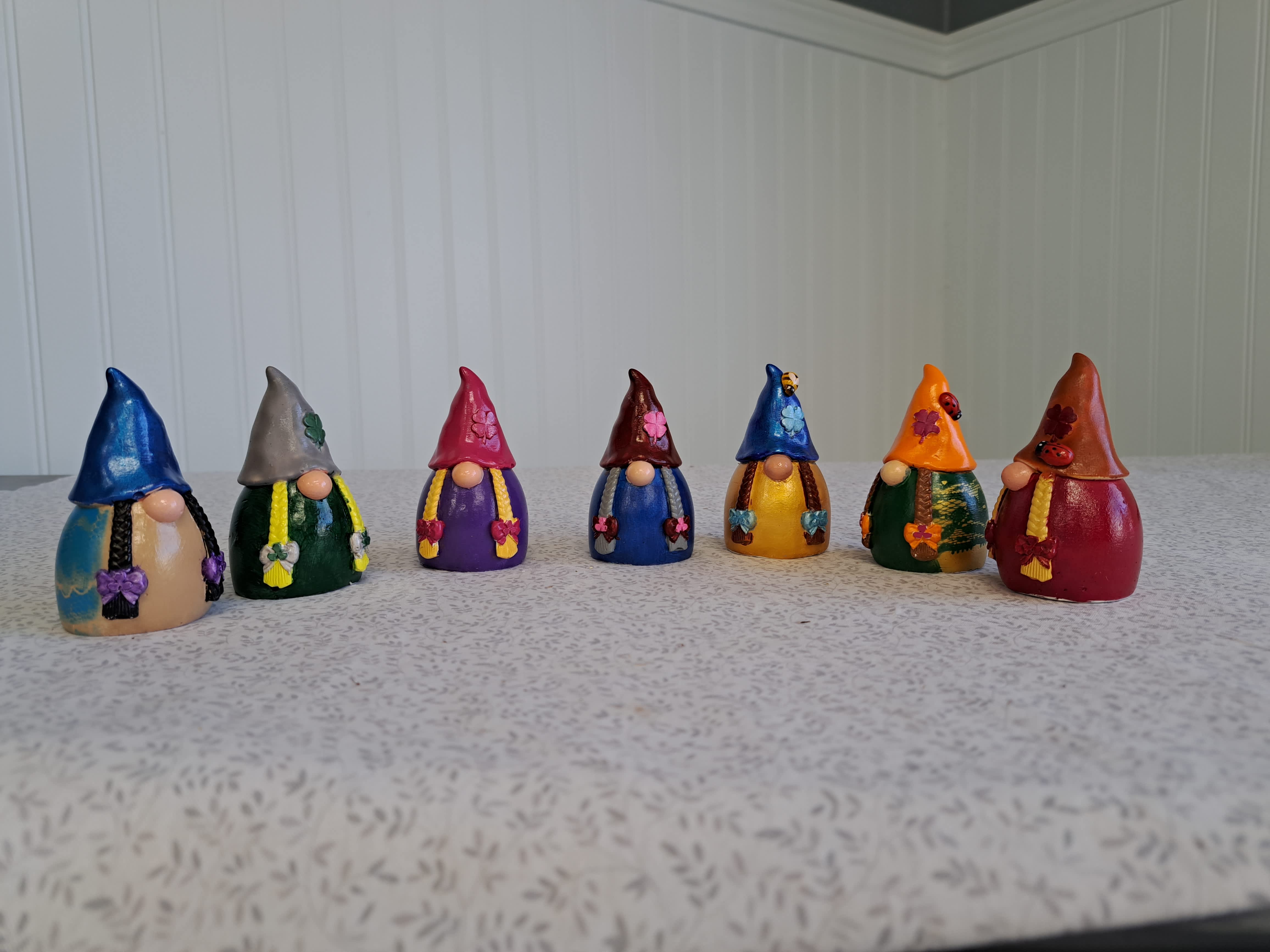 Seven small painted gnome figurines lined up on a tabletop