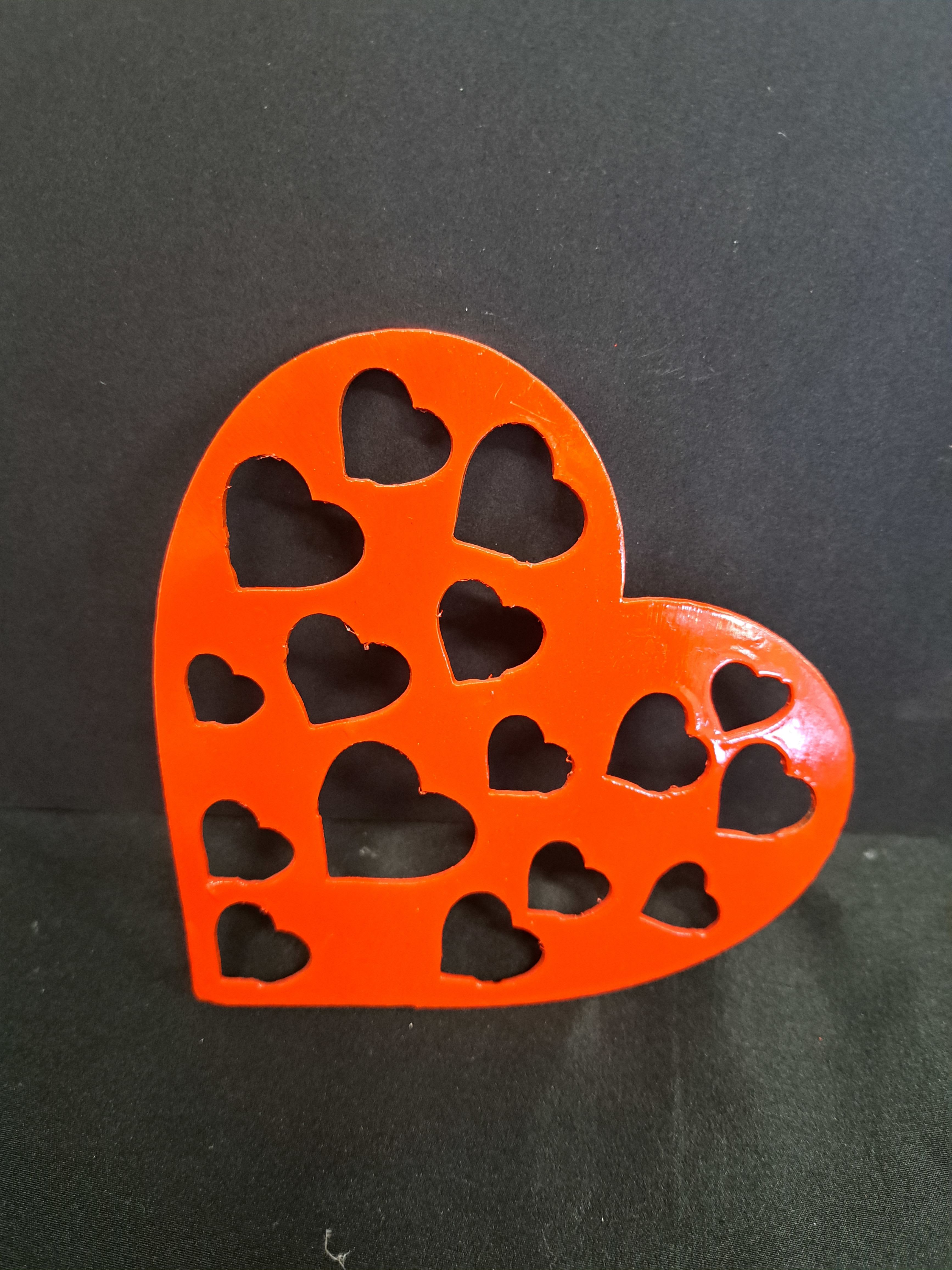 Metal Heart wall hanger Cut out heart - A glossy red heart-shaped metal wall hanger with playful heart cutouts brings instant warmth to a Valentine's Day display or anniversary surprise. This decorative heart sign reads as a light, romantic accent that says "thoughtful" without being fussy - the kind of piece that makes the person you're thinking of feel noticed and loved.