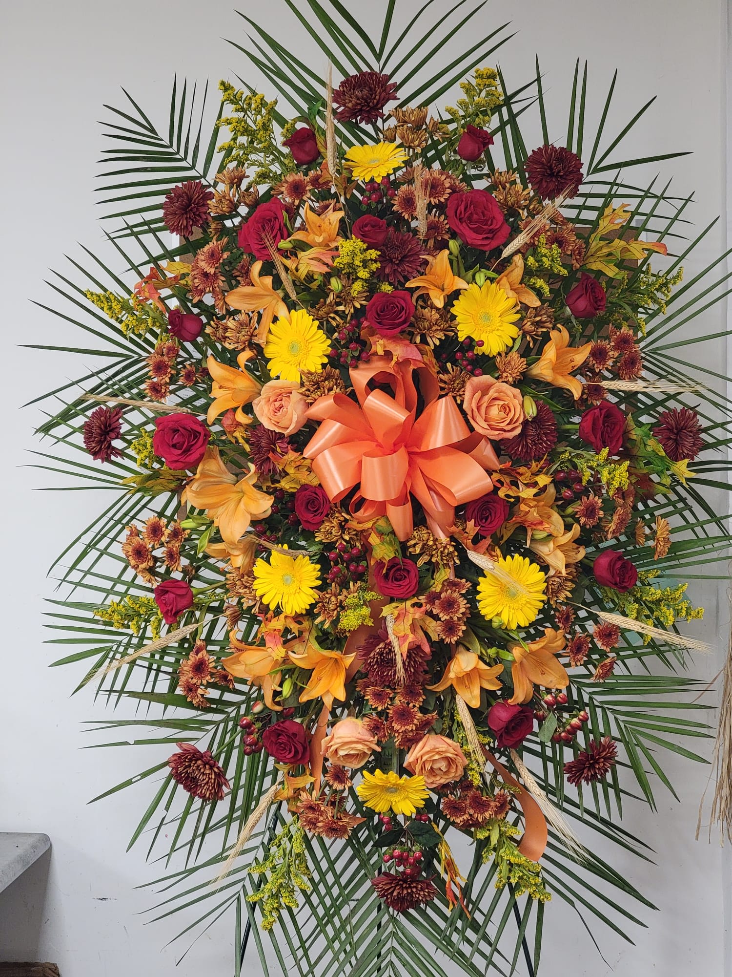 Large standing floral spray with roses, lilies, and yellow daisies