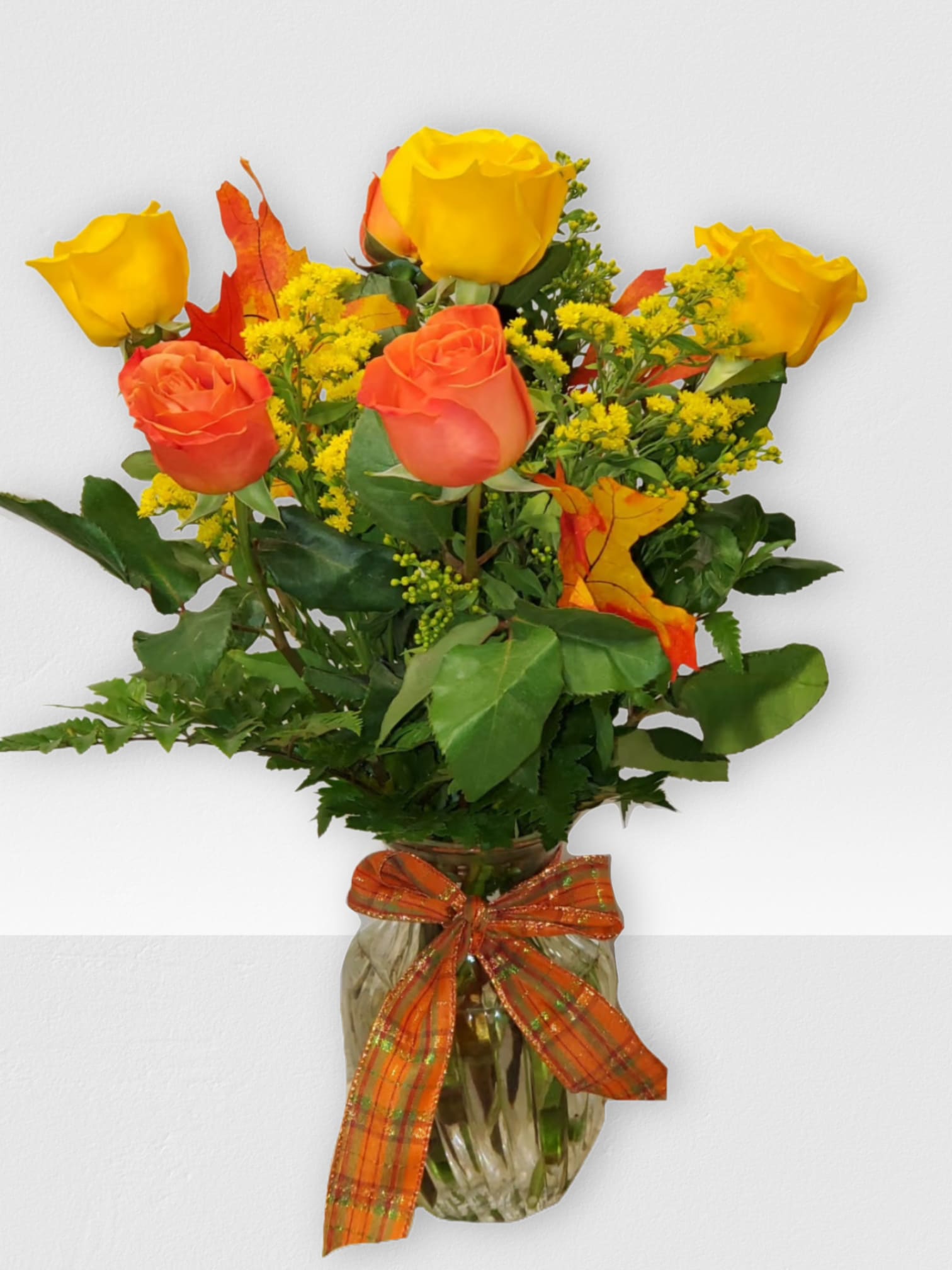 Orange and yellow roses in a glass vase with an orange ribbon