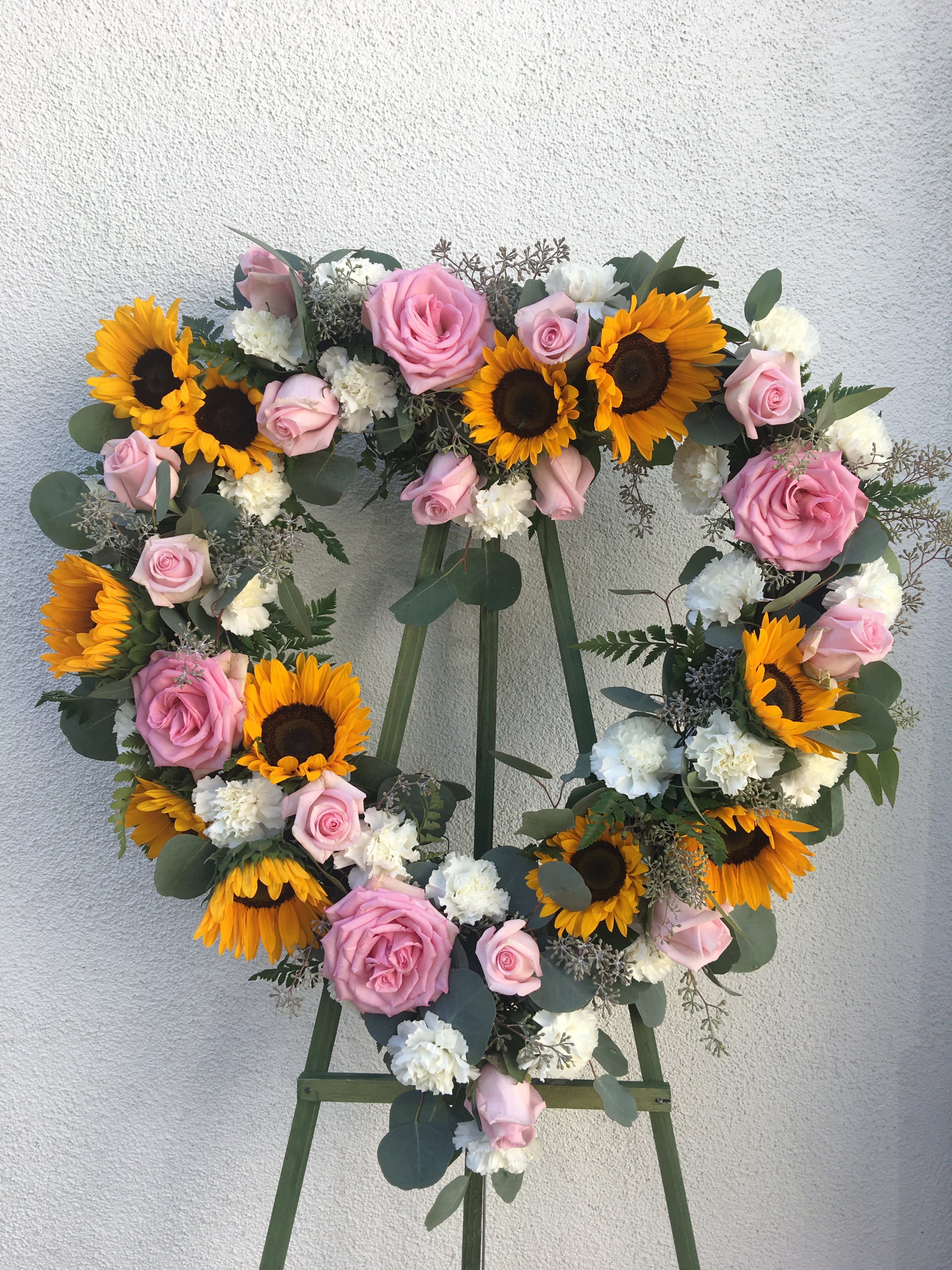 Sunflower Heart - Pink roses, white carnations, and sunflowers on an 18" open heart. pictured is medium small, med, large 