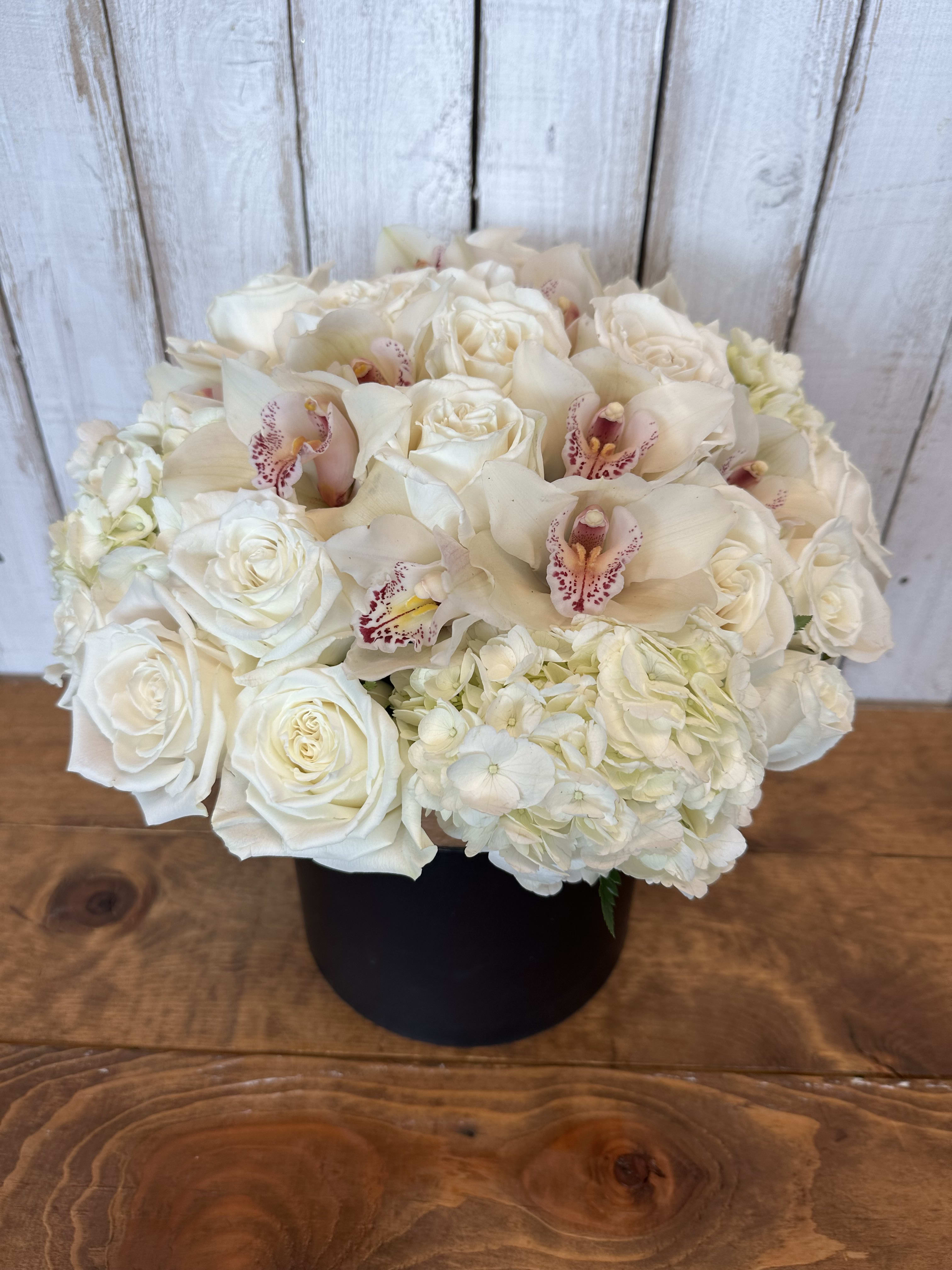 White roses and orchids arranged in a black box