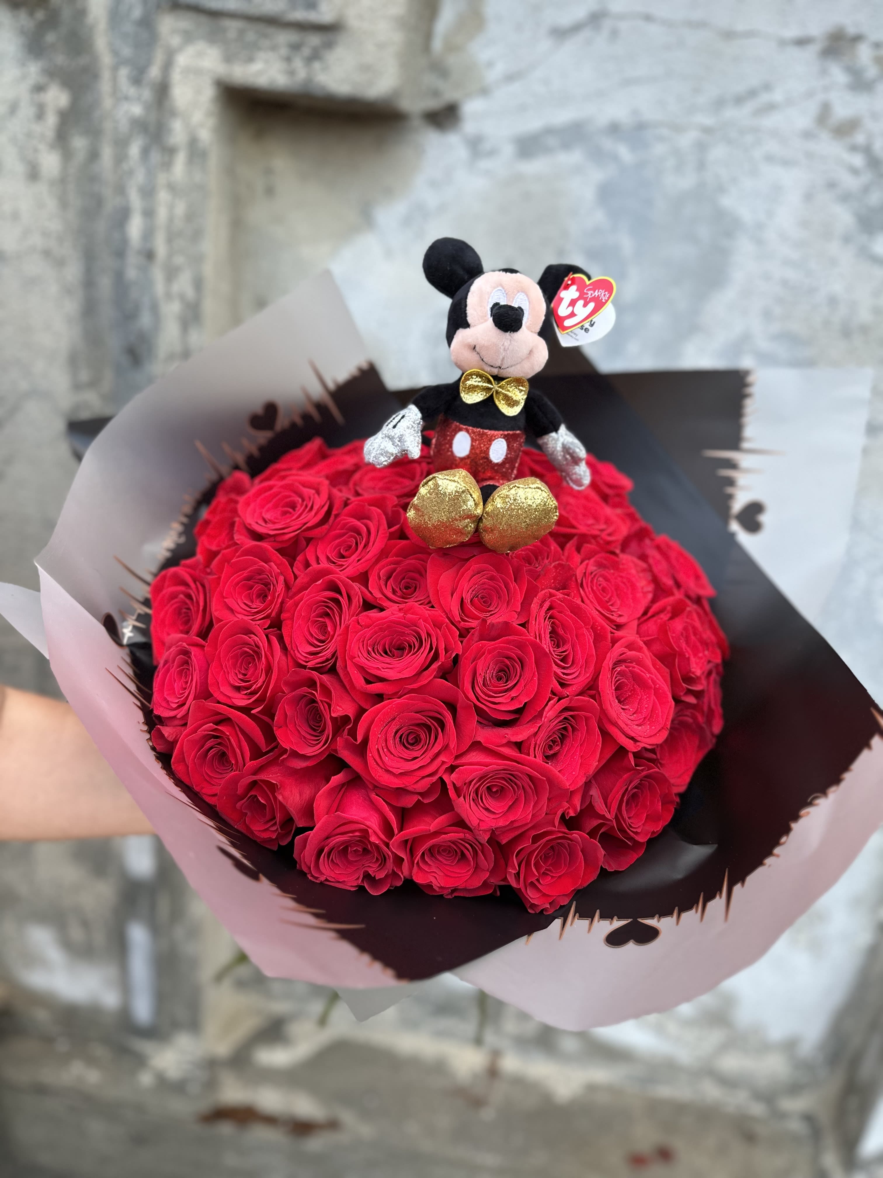 Bouquet of red roses topped with a small Mickey Mouse plush