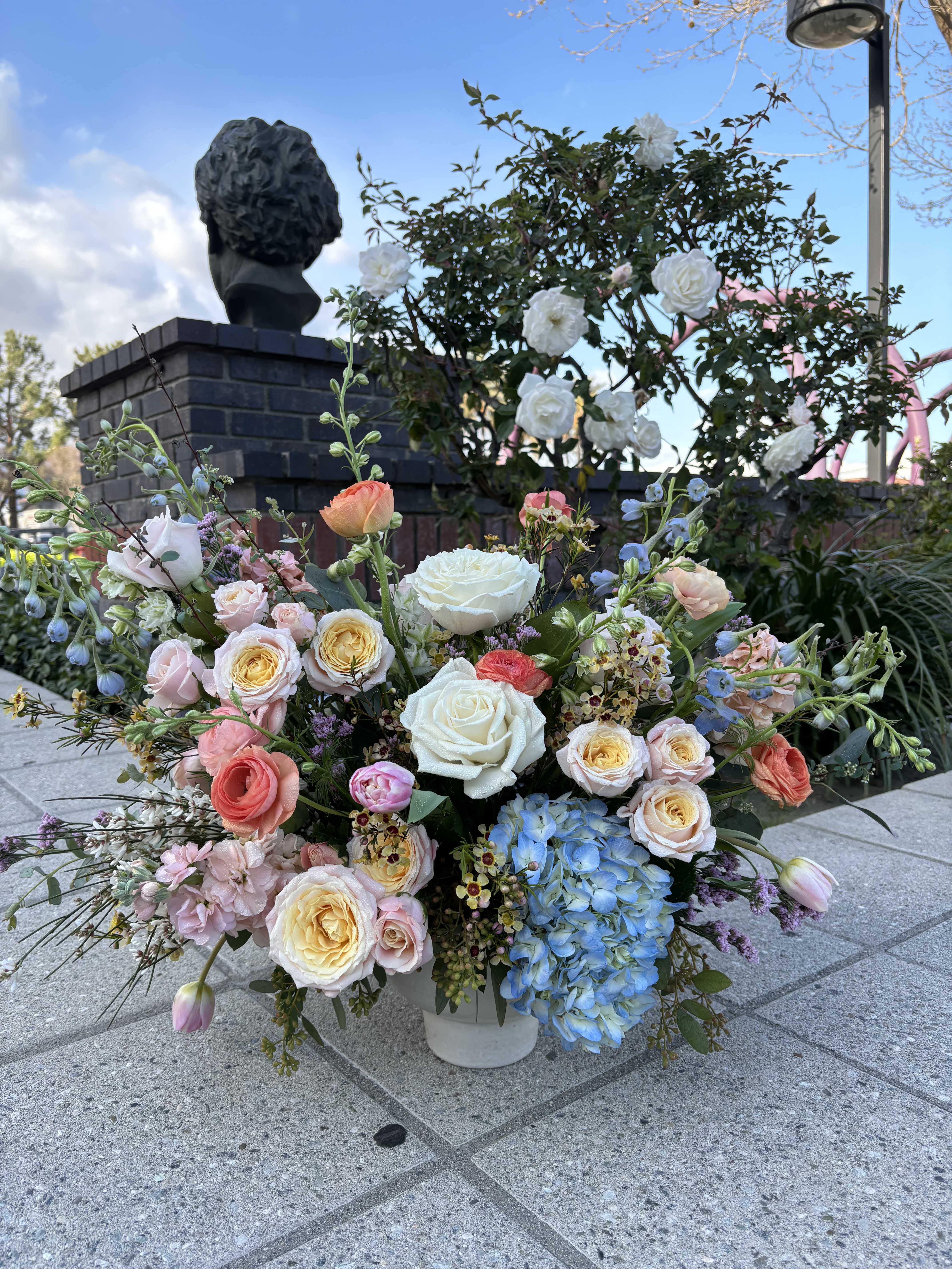Large mixed bouquet of roses, hydrangea, and tulips in a white container