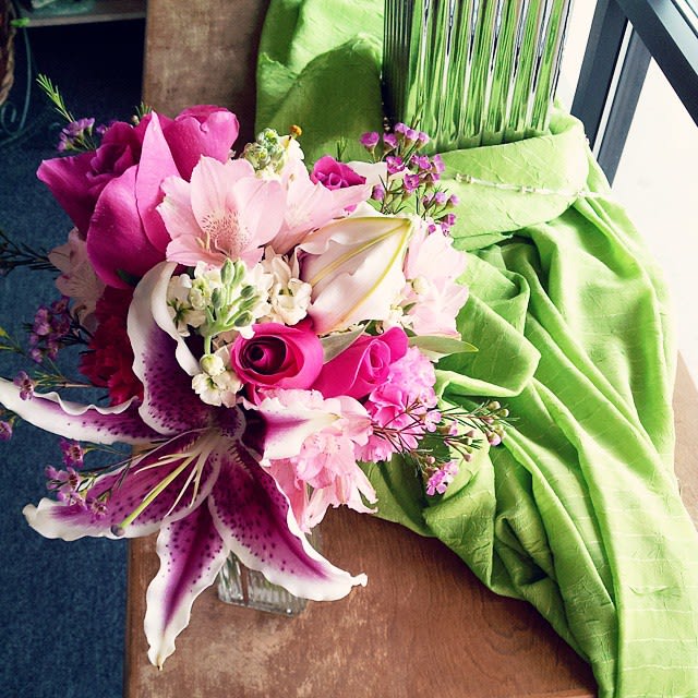 Pink and white bouquet with lilies and roses beside a green draped fabric