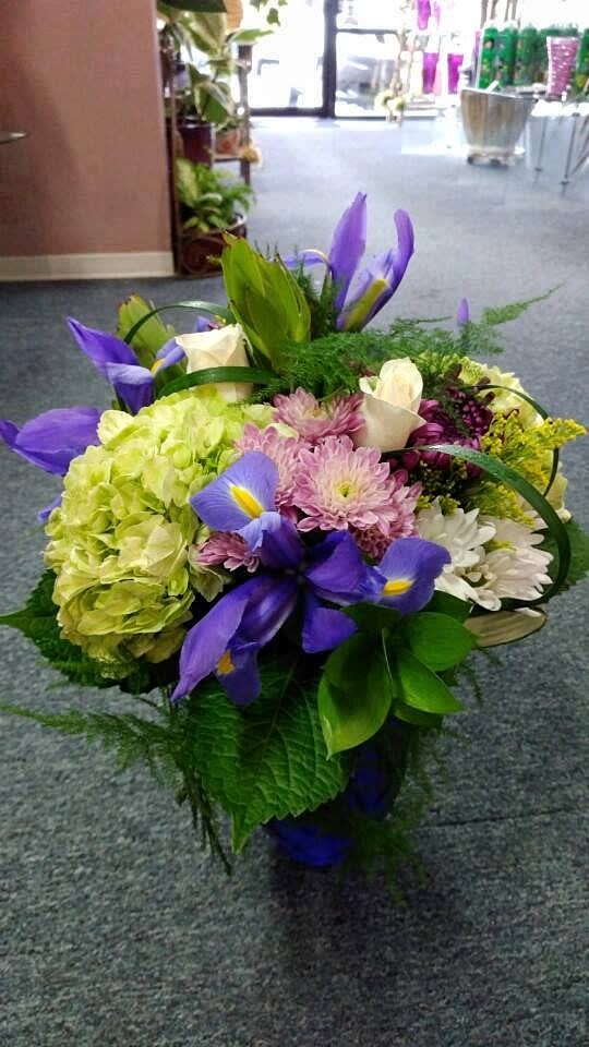 Bouquet of purple irises, hydrangeas, and mixed blooms in a basket