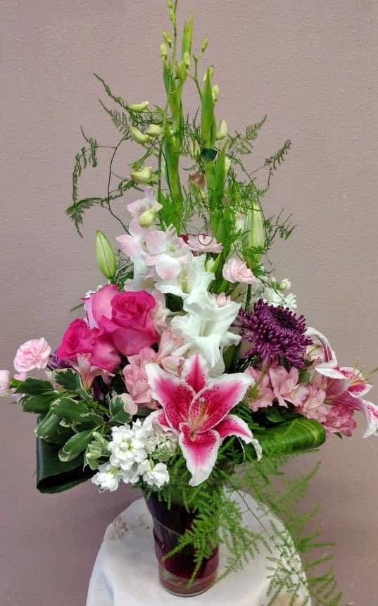 Pink and white mixed flower arrangement in a dark vase