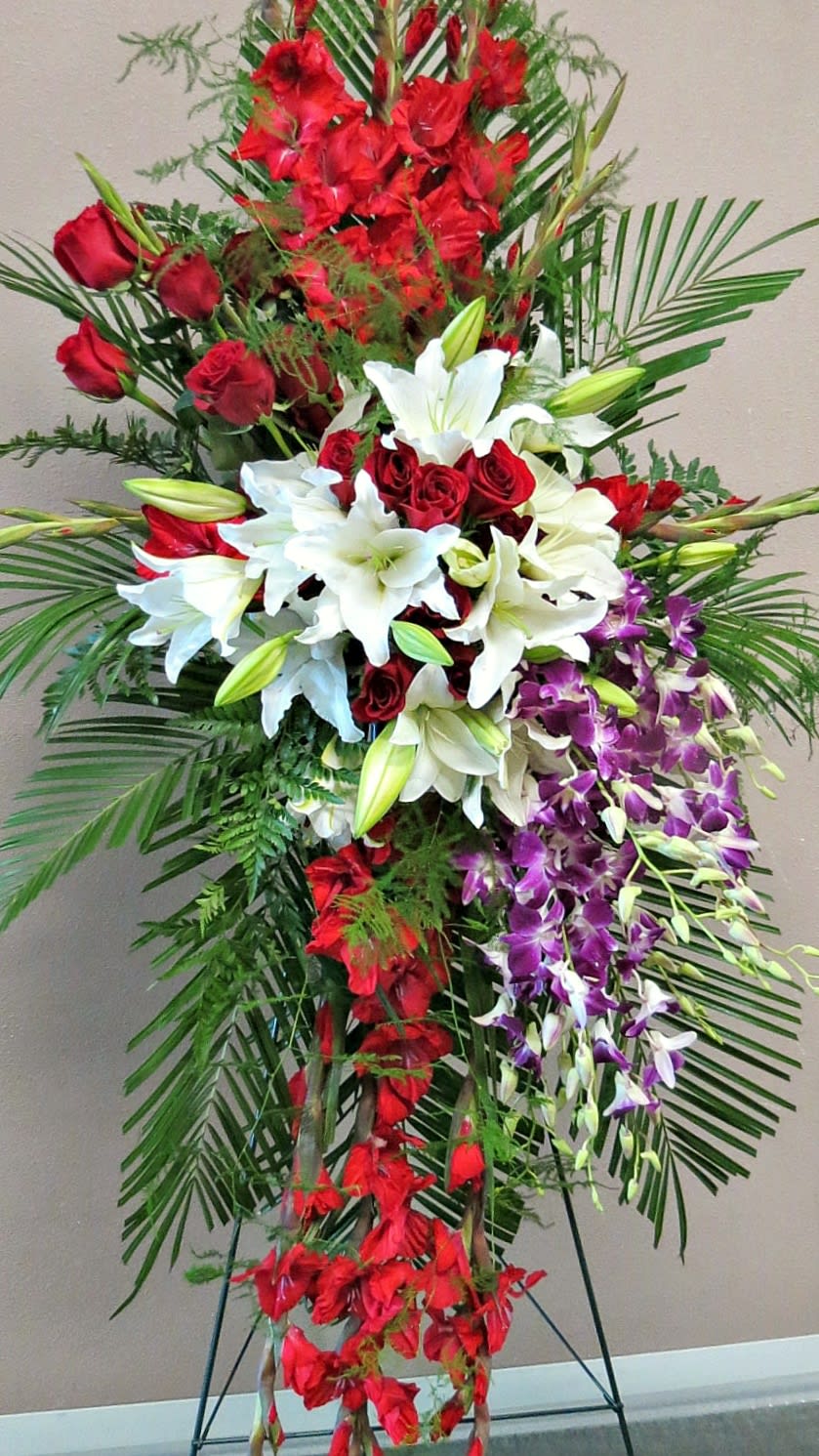 Tall standing floral spray with red roses, white lilies, and purple orchids