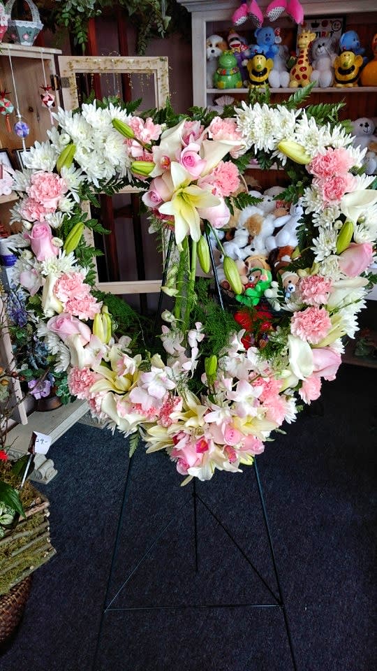 Heart-shaped floral wreath on a stand with pink and white flowers
