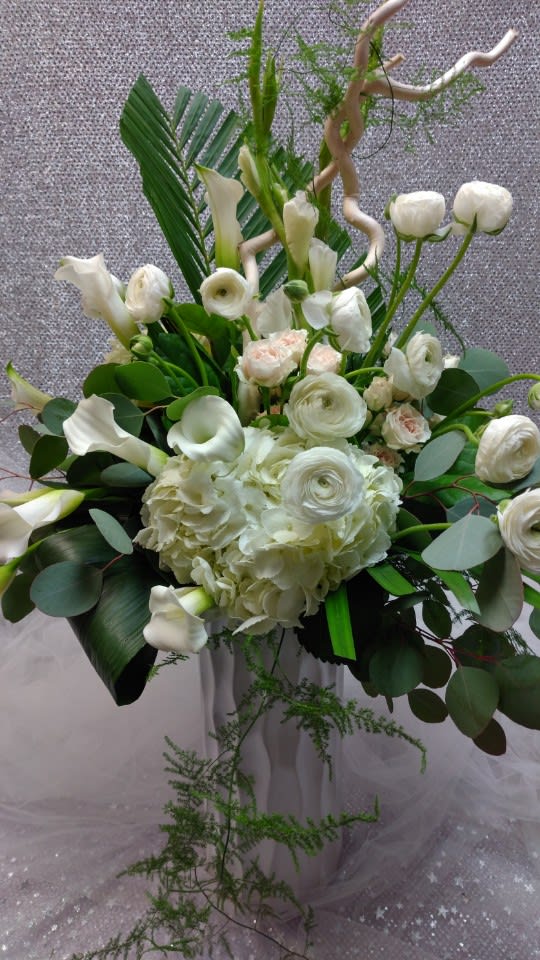 White floral arrangement with calla lilies, ranunculus, and hydrangea