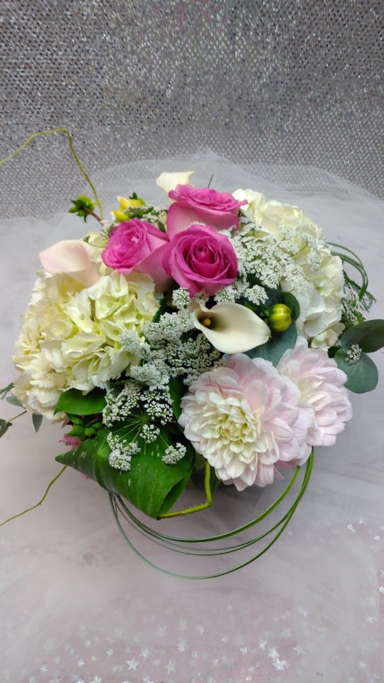 Pink roses and pale blooms arranged with white calla lilies in a bouquet