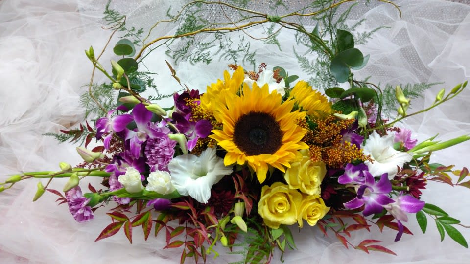 Mixed bouquet with a sunflower, yellow roses, and purple orchids