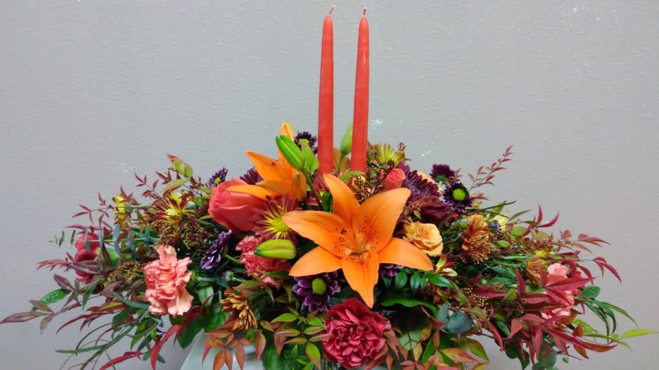 Bright floral arrangement with orange lilies and two red candles