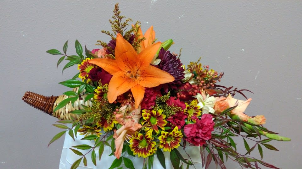Bouquet with orange lily and mixed flowers in a woven handle wrap