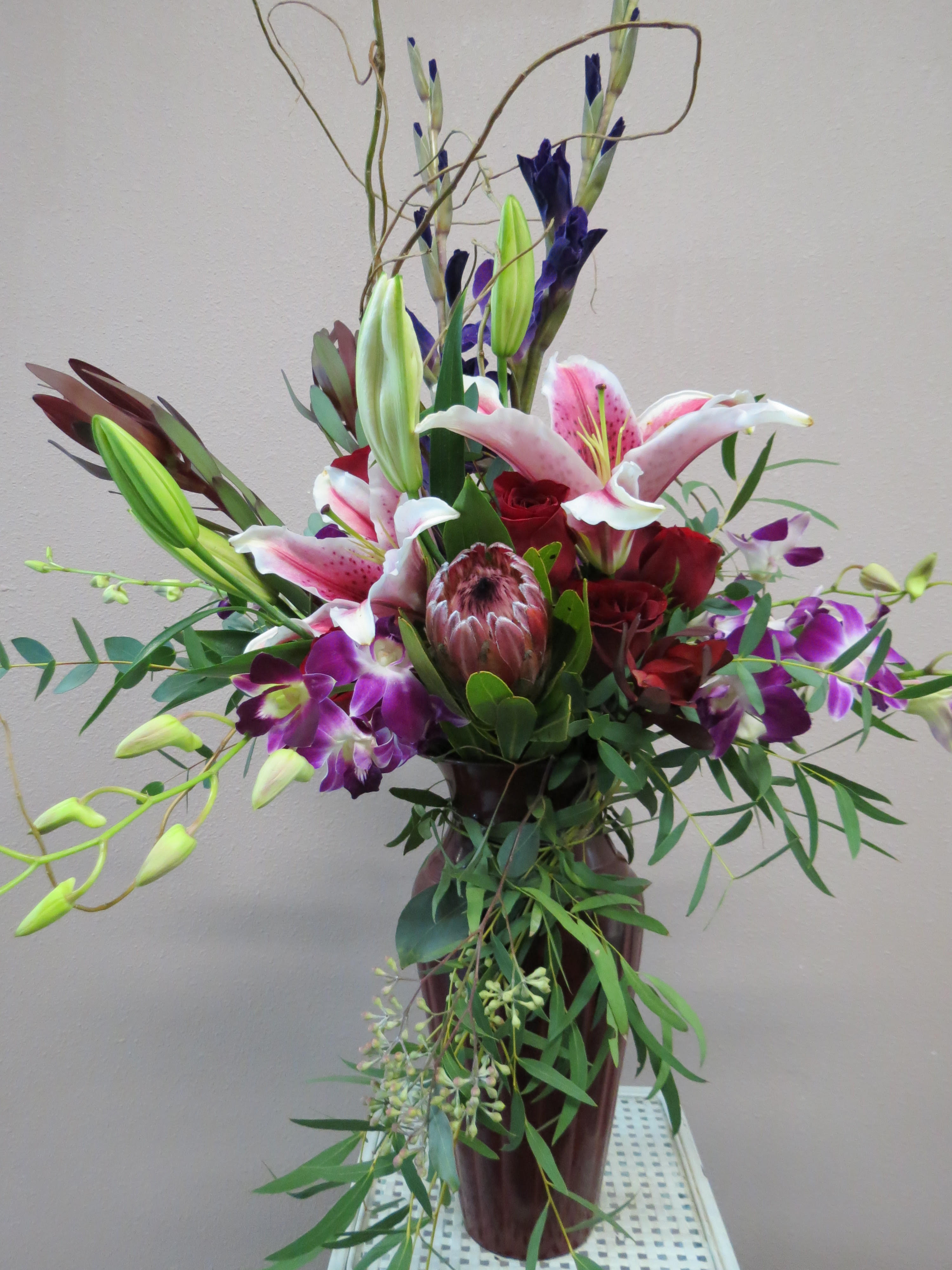 Tall bouquet of lilies, roses, and orchids in a vase