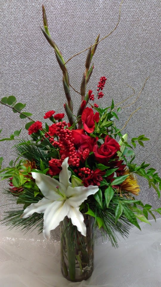 Red roses and white lilies in a glass vase with tall decorative branches