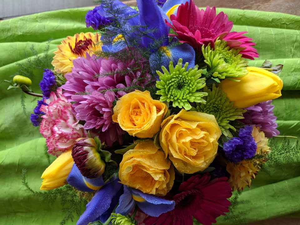 Bright mixed bouquet with roses, daisies, and tulips on green fabric