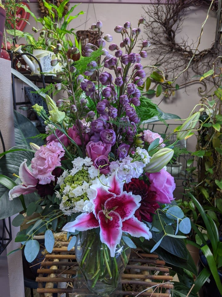 Mixed bouquet with pink lilies, roses, and purple blooms in a glass vase