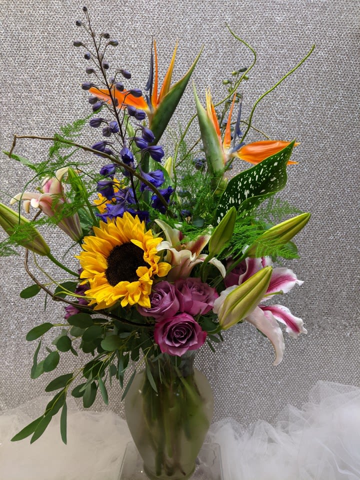 Mixed bouquet with sunflowers, roses, lilies, and bird of paradise in a vase