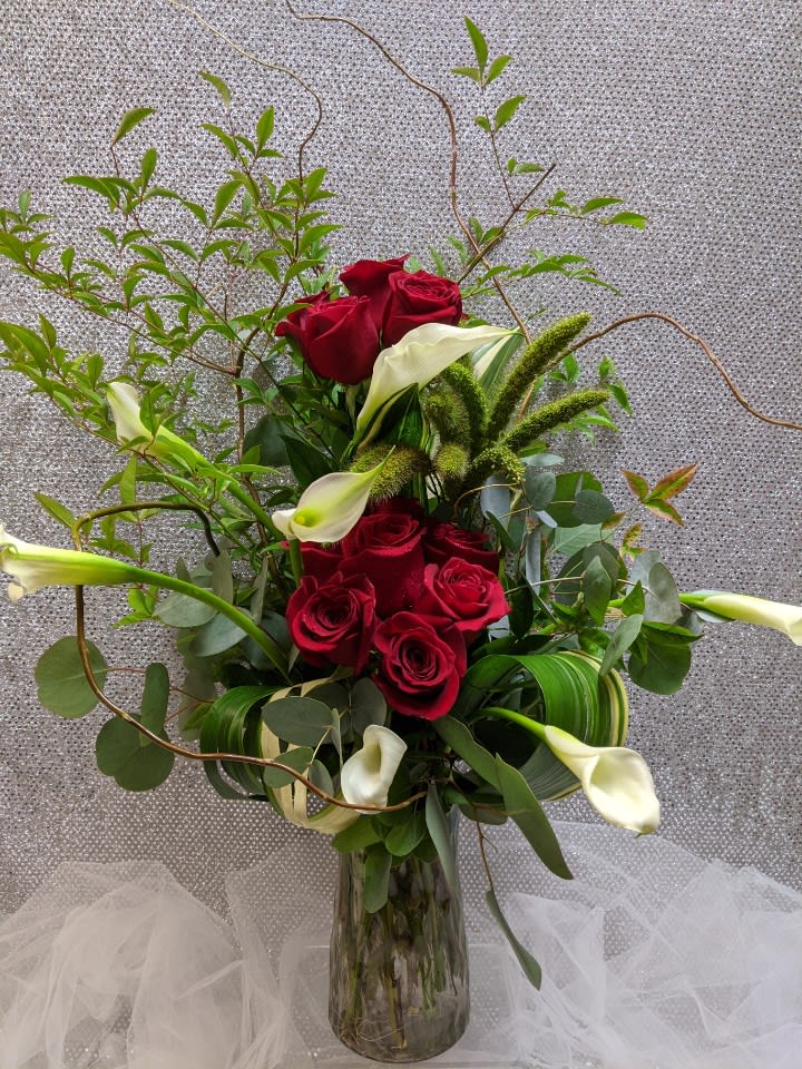 Red roses and white calla lilies in a glass vase