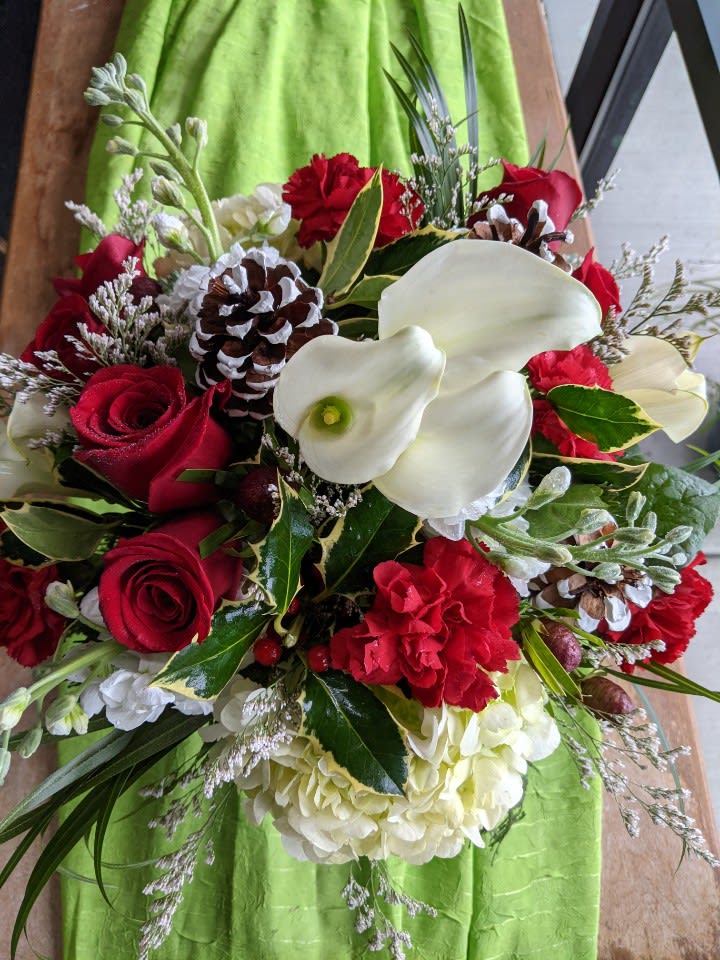 Bouquet of red roses, white calla lilies, and pinecones