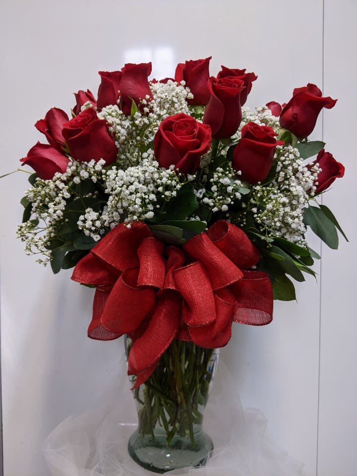 Red roses with baby's breath in a glass vase and red ribbon
