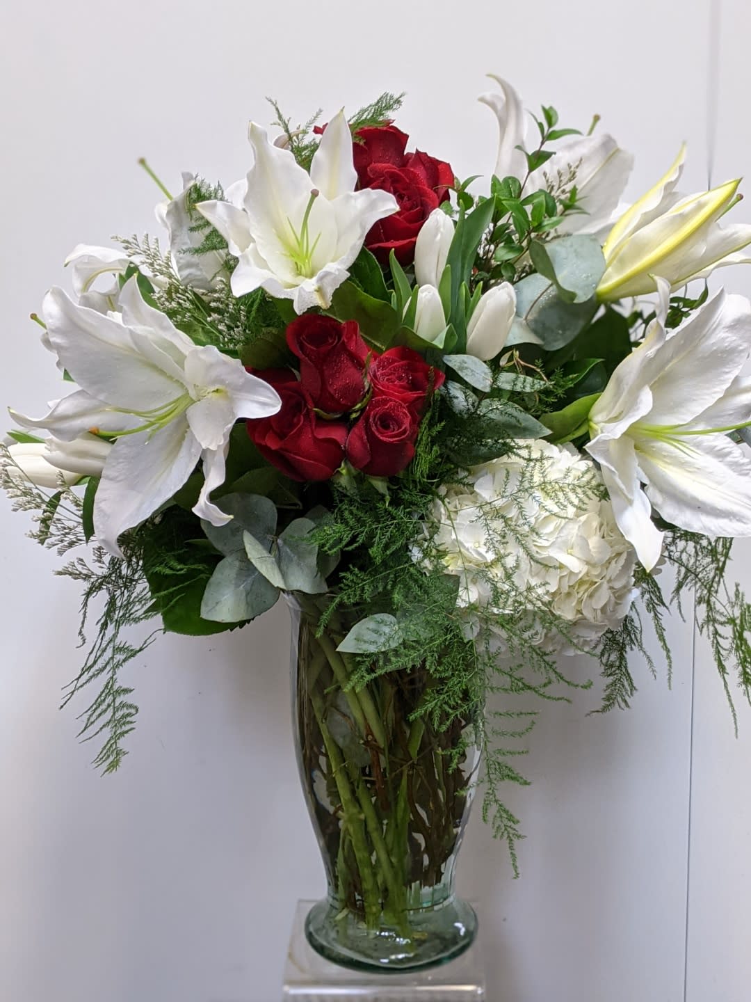 Red roses and white lilies in a clear glass vase