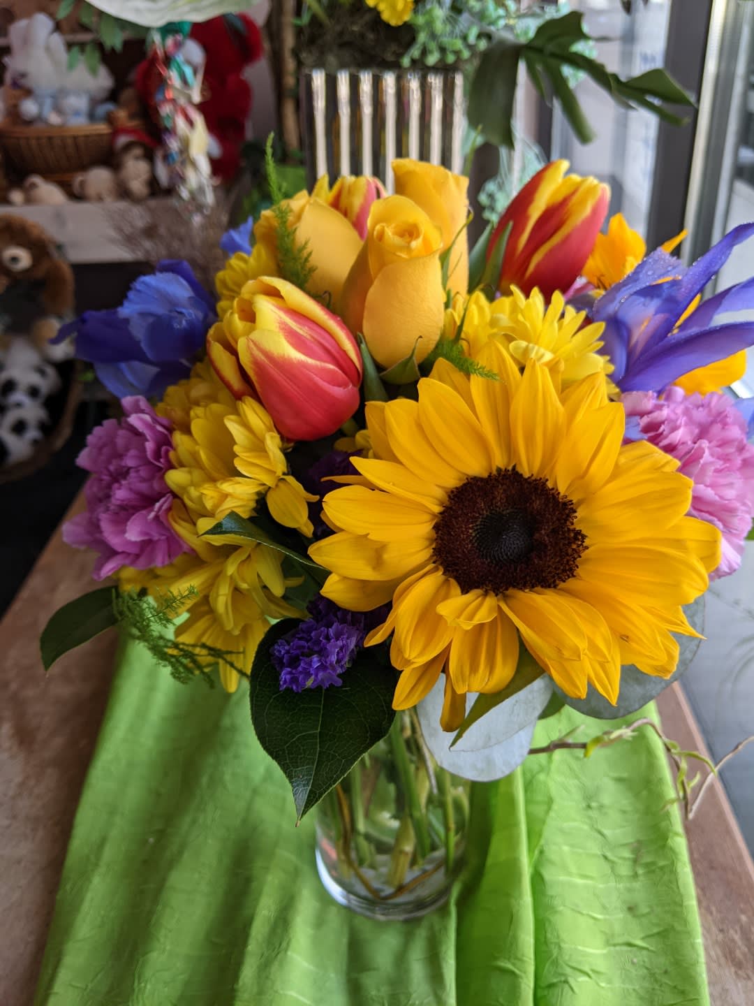 Bouquet of sunflowers, tulips, and purple flowers in a glass vase