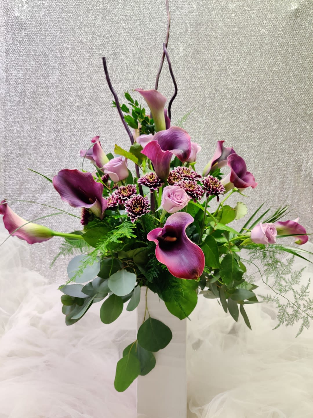 Purple calla lilies and pink roses in a white vase