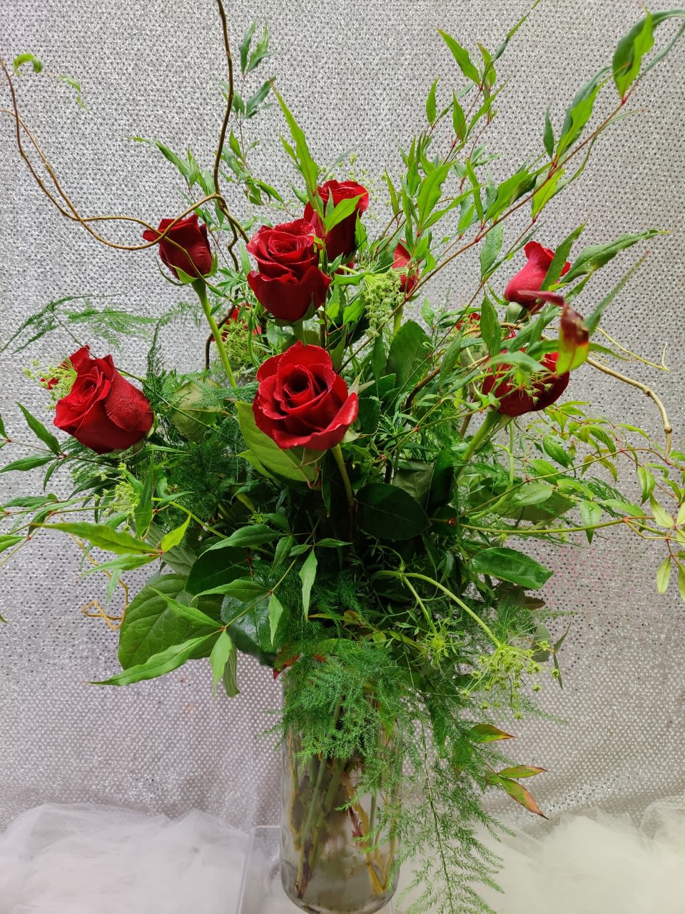Red roses in a clear glass vase with airy greenery