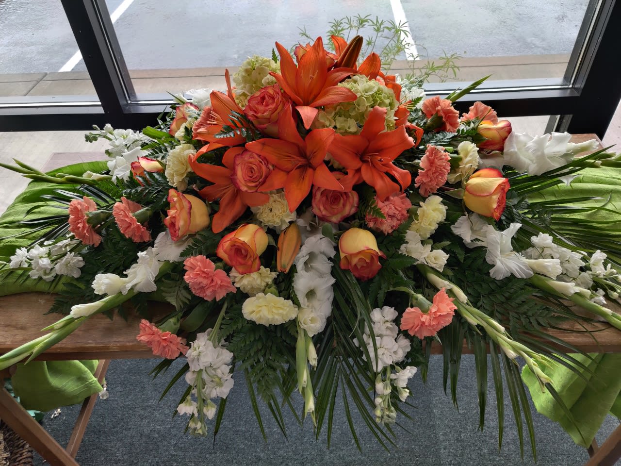 Large floral casket spray with orange lilies and roses