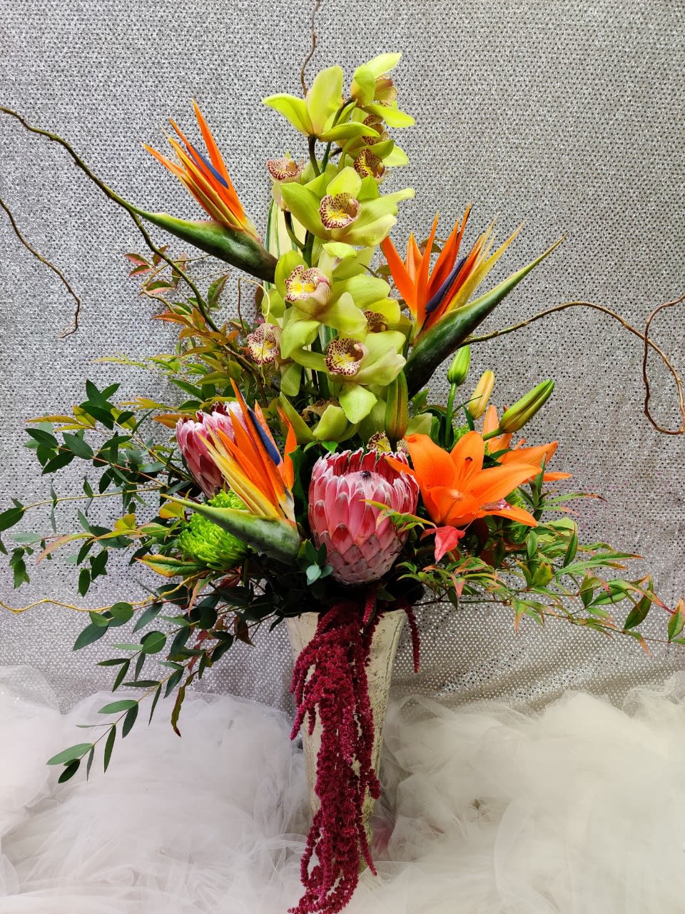 Tall tropical arrangement with orchids, bird of paradise, and lilies in a vase