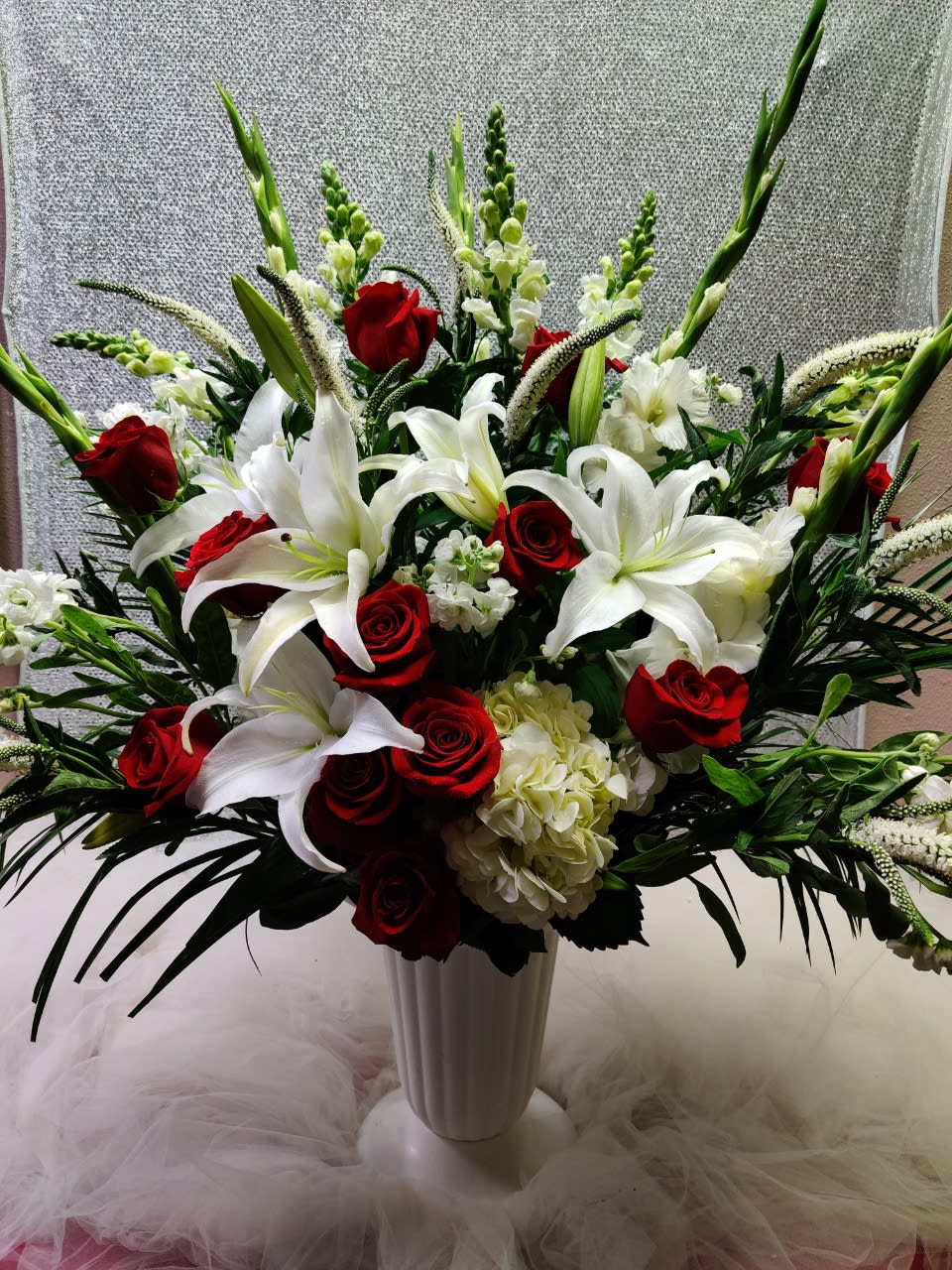 Red roses and white lilies in a tall white vase