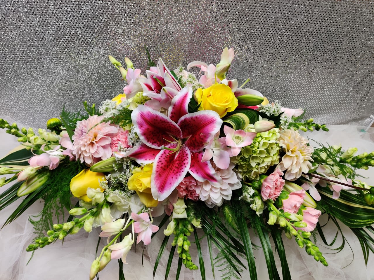 Large floral arrangement with pink lilies, yellow roses, and pastel blooms