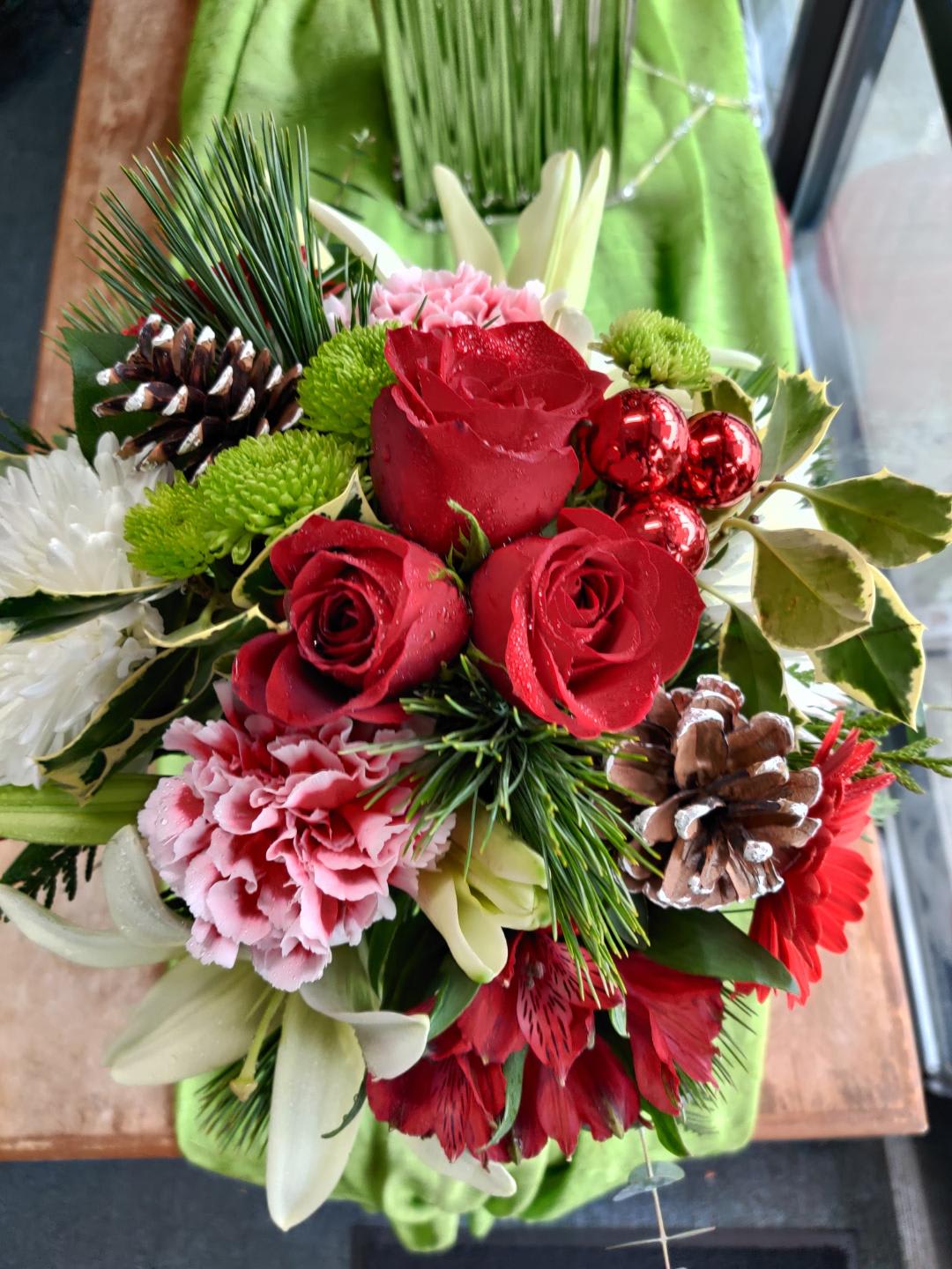 Bouquet of red roses, pink carnations, and white lilies with pinecones
