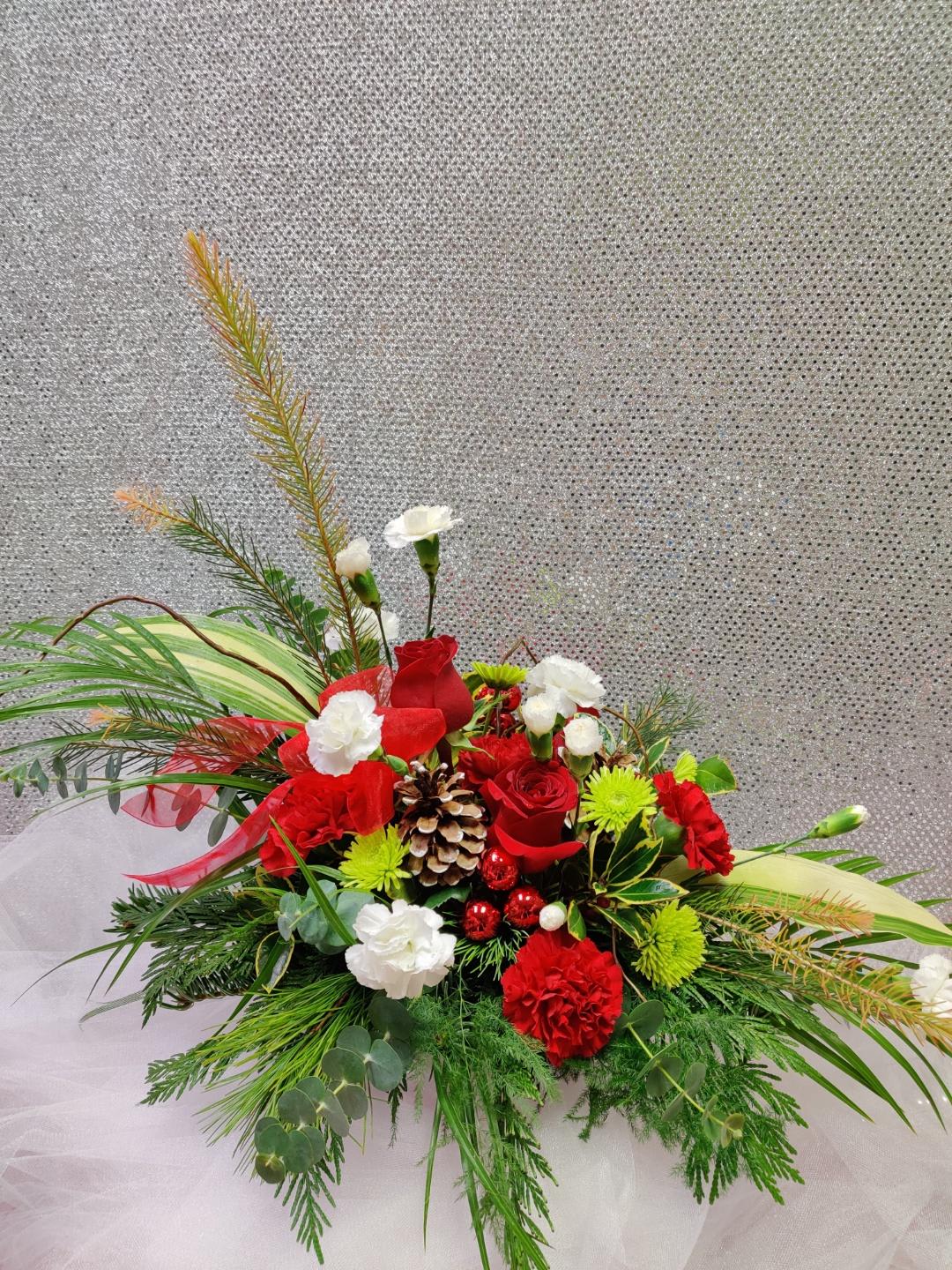 Red and white floral arrangement with pinecones and greenery