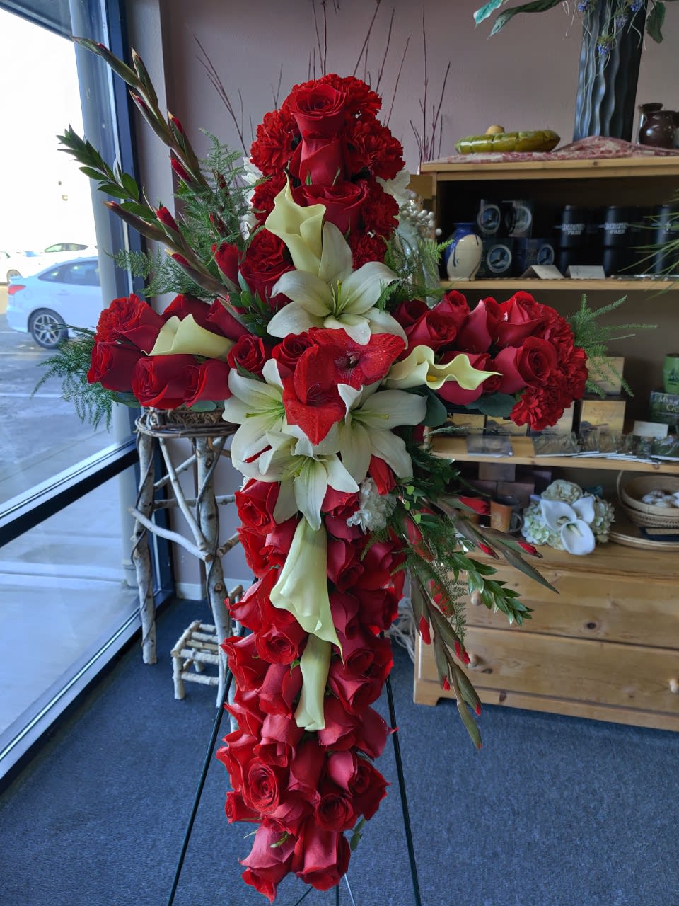 Large red and white floral cross arrangement on a stand