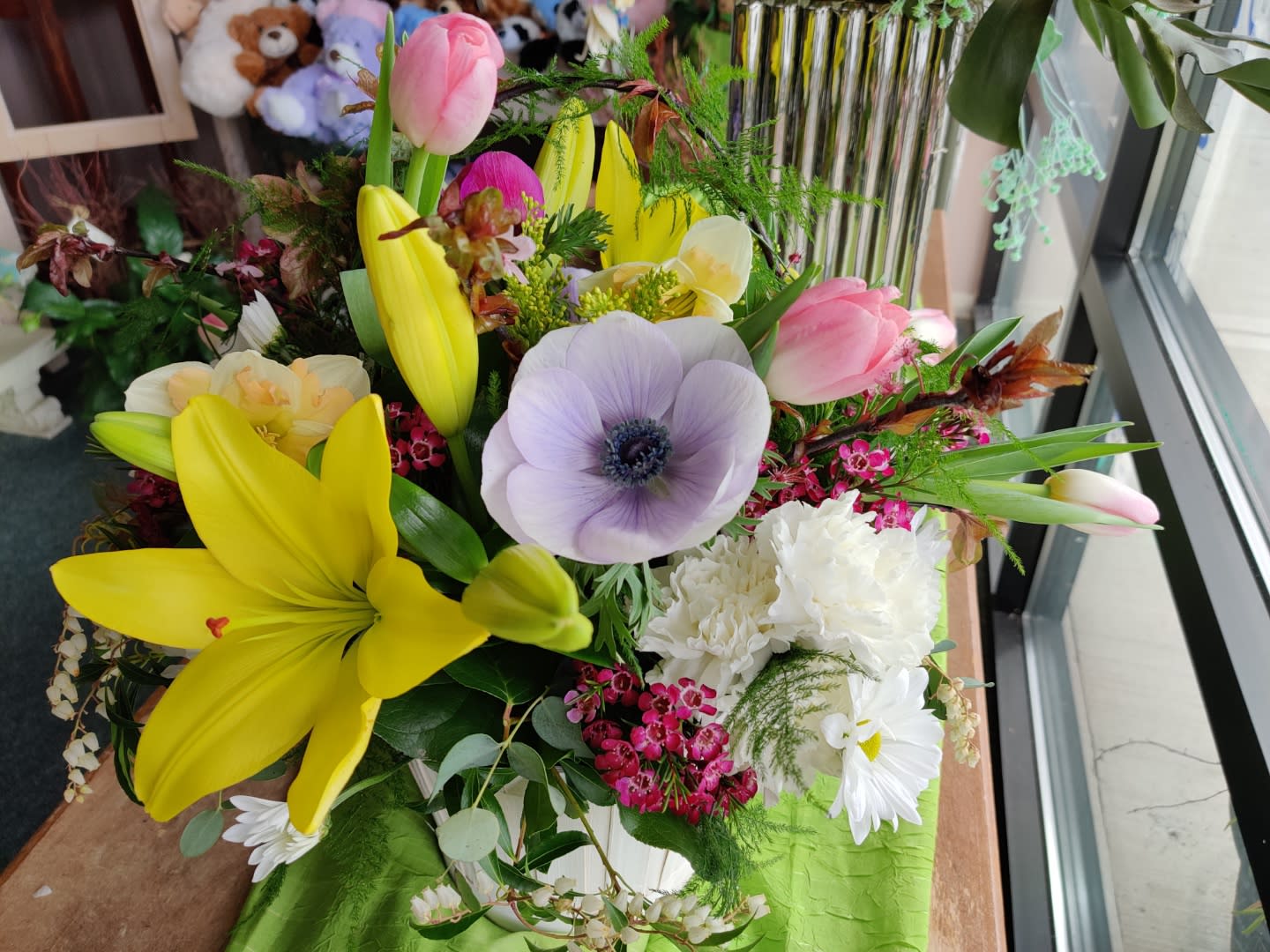 Mixed bouquet with yellow lilies, pink tulips, and a pale purple anemone