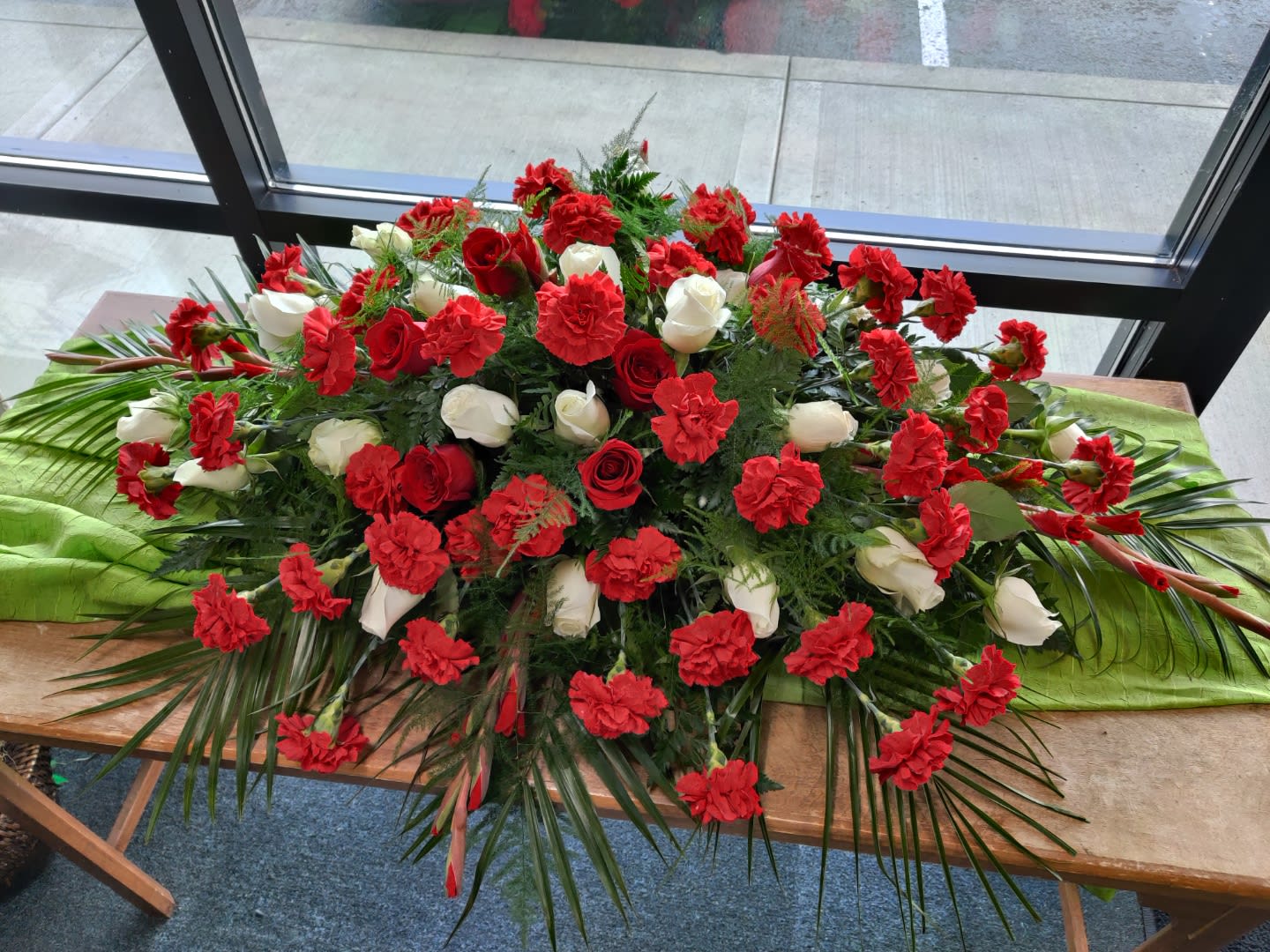 Large red and white floral casket spray on a table