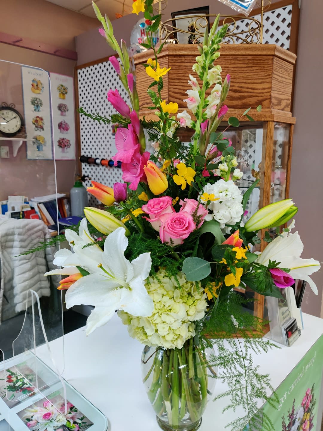 Tall mixed bouquet with lilies, roses, hydrangea, and snapdragons in a glass vase