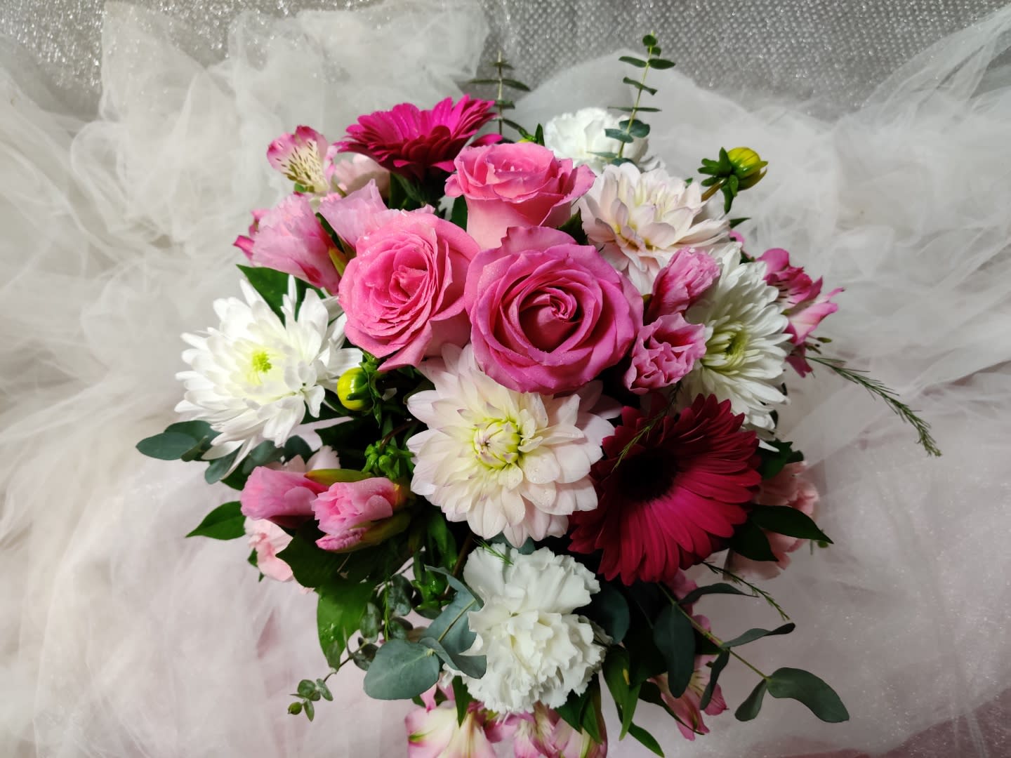 Pink roses and white daisies arranged in a bouquet with tulle wrapping