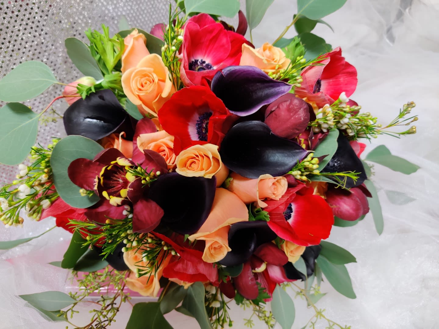 Bouquet of red and peach flowers with dark calla lilies