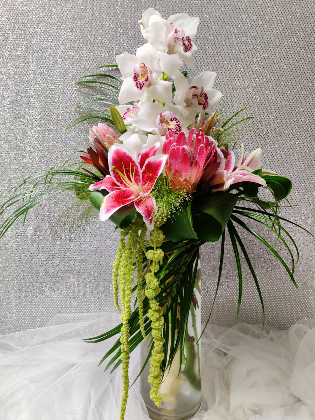 A Beautiful Smile - Includes Cymbidium orchids, Protea, Stargazer lilies, Safari sunset, Amaranthus in a Tall Vase 
